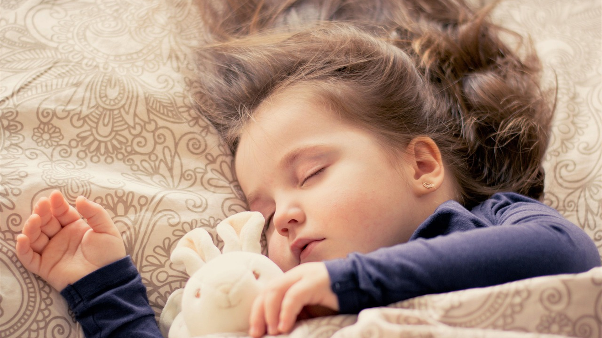 Young child asleep in bed with hair fanned across the pillow, illustrating restless sleep as one of the first signs of lice