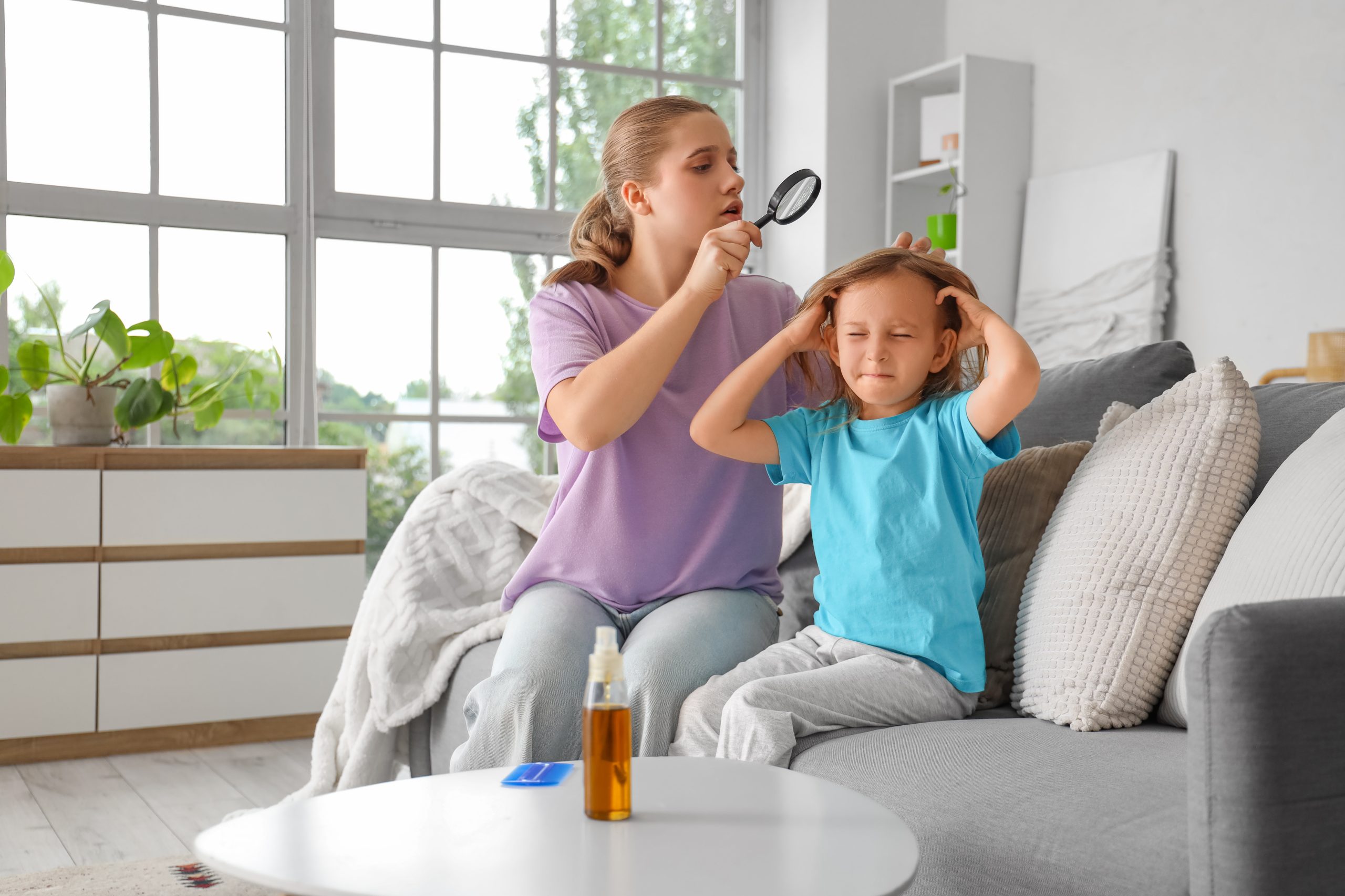 Bucks County mother using a small magnifier to check her daughter's hairline and lash line for lice and nits during a careful at-home screening.