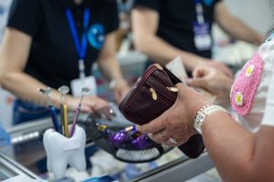 Customer at a professional clinic reception holding a wallet while reviewing the cost of a paid service