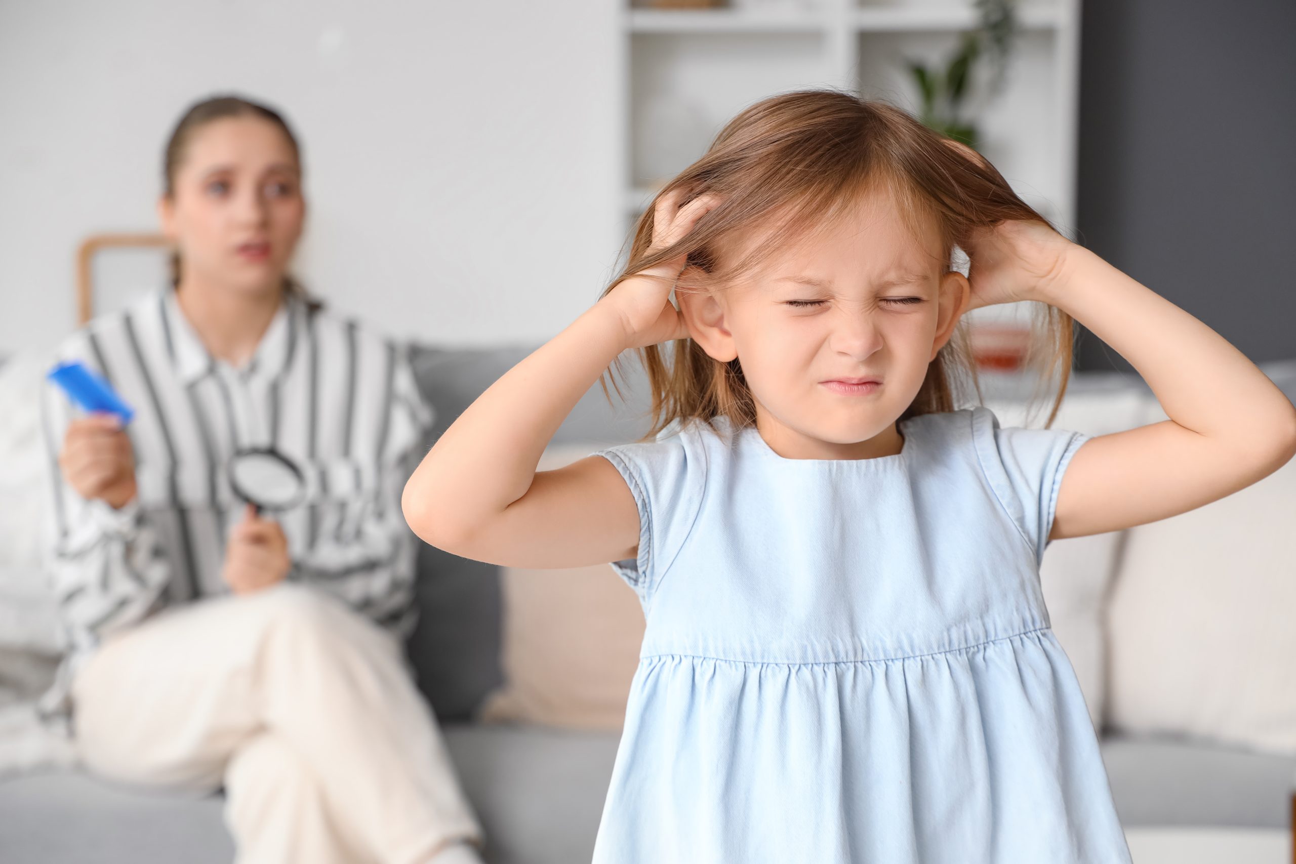 A young child scratching an itchy scalp at home while dealing with head lice