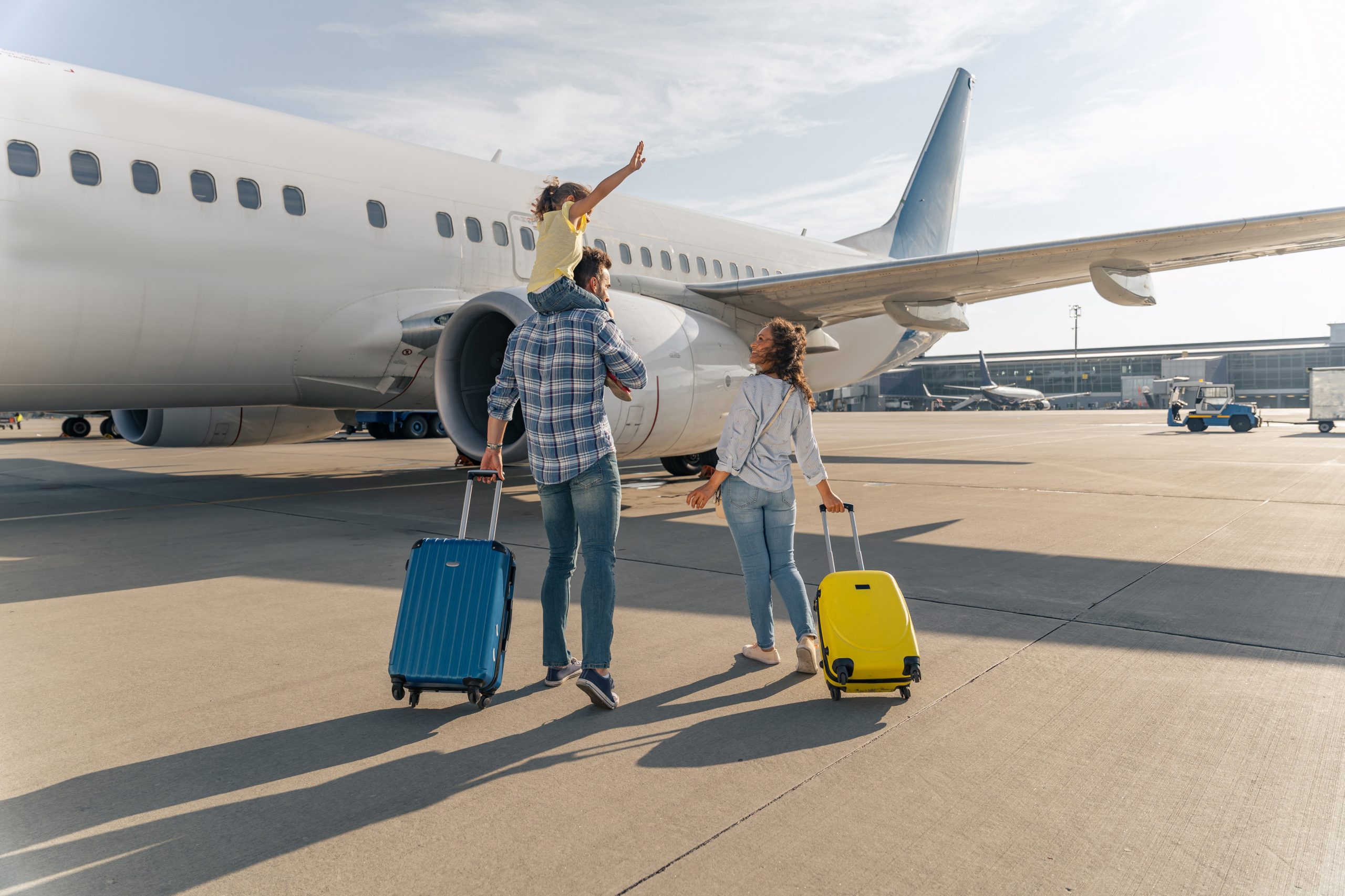 Family with luggage boarding a plane for spring break travel.