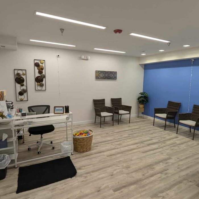 Treatment image by Lice Lifters Of Bucks County - Lice Treatment and Lice Removal Wide interior view with a desk, wall seating, shelving and a blue accent wall.